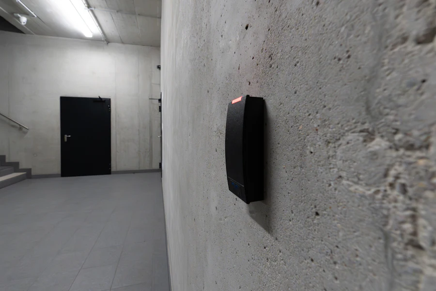 Card reader mounted on a concrete wall beside a dark doorway