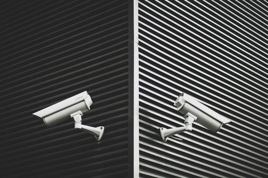 Two security cameras mounted on a ribbed dark wall