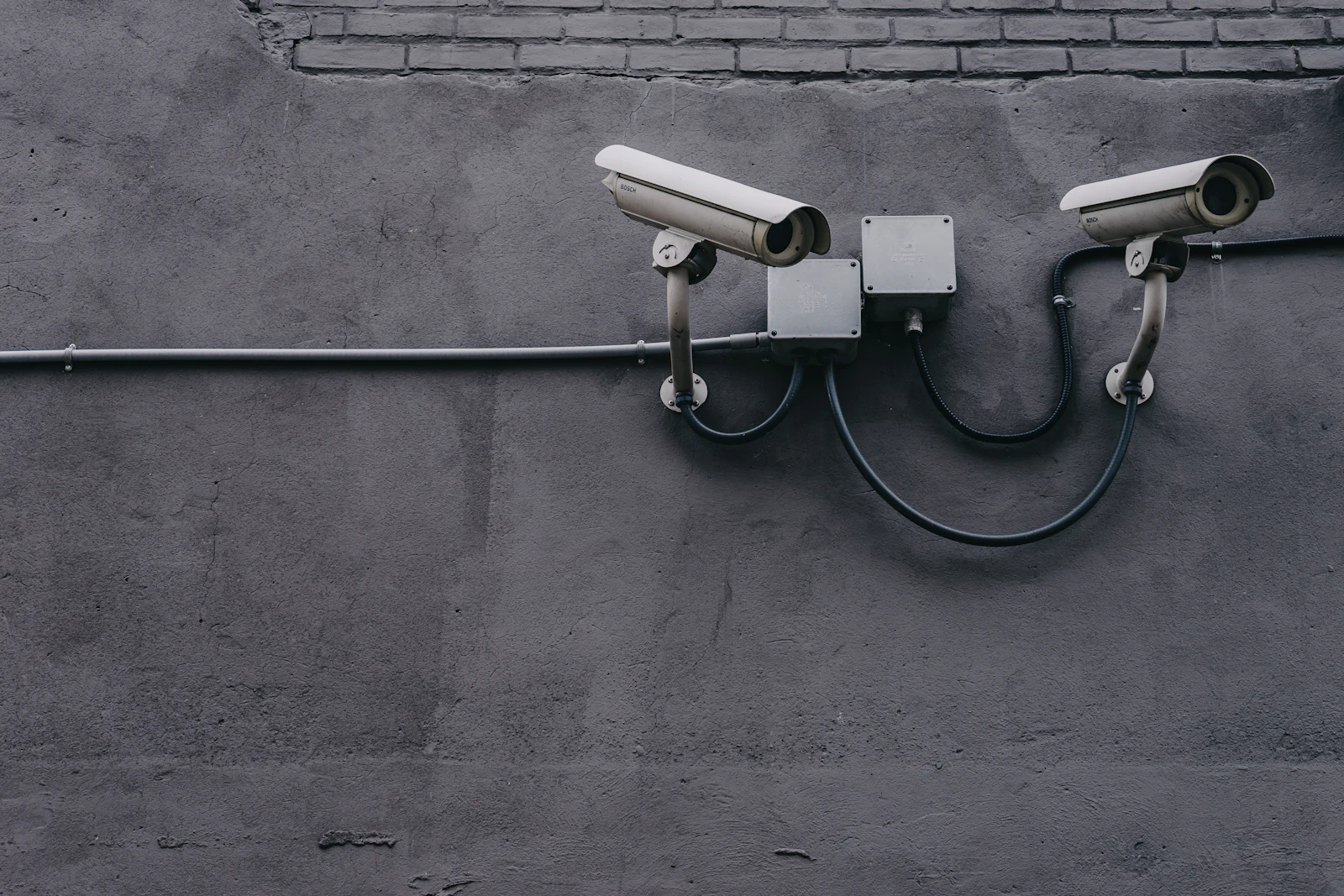 Two bullet surveillance cameras mounted on a grey wall