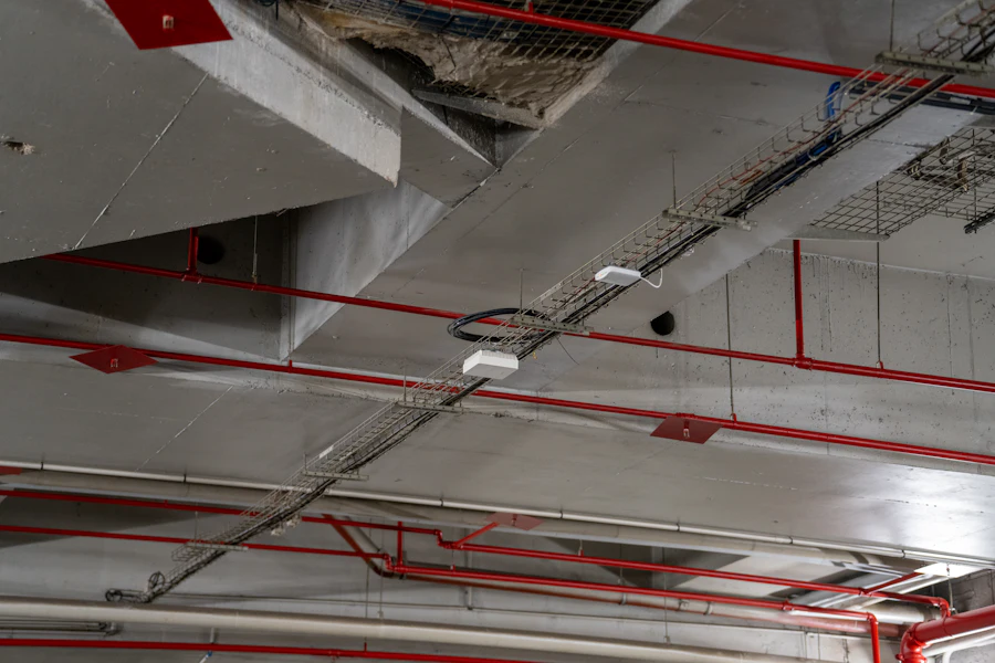 Exposed concrete ceiling with red sprinkler pipes and cable trays