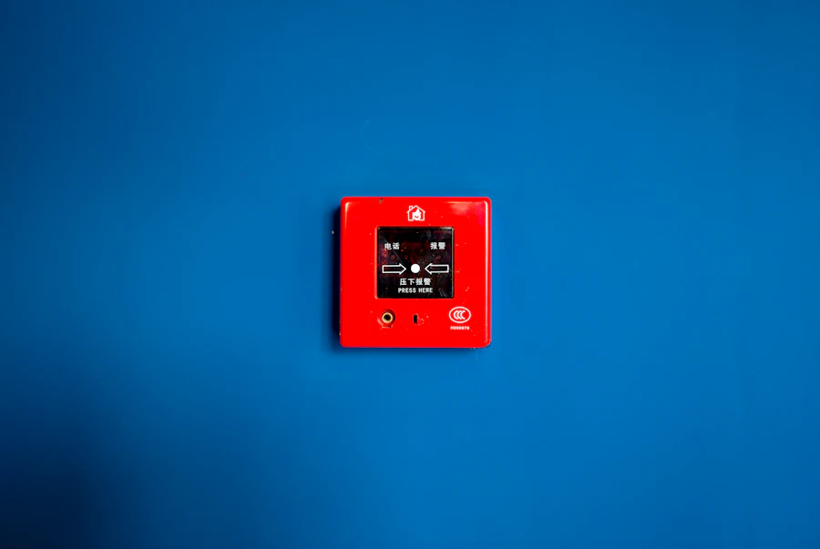Red manual fire alarm pull station mounted on a blue wall
