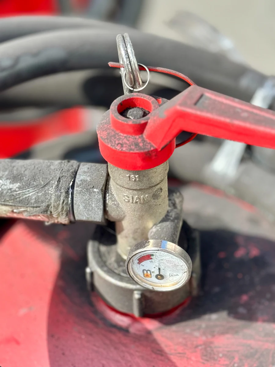 Close-up of a red suppression cylinder valve with a pressure gauge